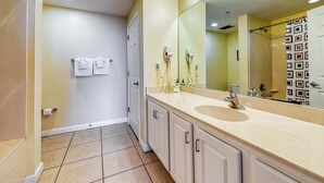 A bathroom with a beige sink, a large mirror, and a shower curtain.
