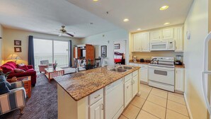 A spacious living area with a kitchen, a dining table, and a red sofa.