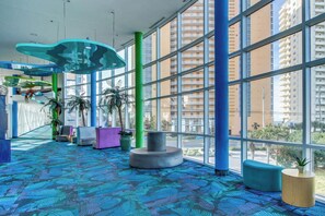 A spacious lobby with large windows, a patterned carpet, and modern seating areas. - Beachfront, high-end condo with Pool, Hot tub & Splash pad (Panama City Beach)