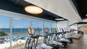 A gym with treadmills and exercise bikes, large windows with a beach view. - Beachfront, high-end condo with Pool, Hot tub & Splash pad (Panama City Beach)