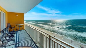 A balcony with a view of the ocean, featuring a seating area with chairs and a table. - Beachfront, high-end condo with Pool, Hot tub & Splash pad (Panama City Beach)