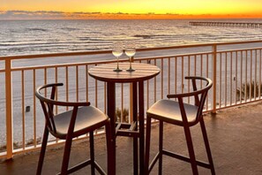 Un balcón con dos sillas y una mesa, con vistas al agua y al muelle.