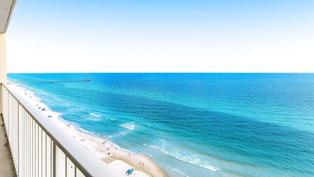 A beach view from a balcony with a clear sky and a pier in the distance. - Picturesque 18th-floor gulf-front condo w/ pools, hot tubs & beach service (Panama City Beach)