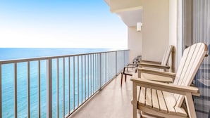 A balcony with a view of the ocean, featuring two wooden chairs and a small table. - Picturesque 18th-floor gulf-front condo w/ pools, hot tubs & beach service (Panama City Beach)