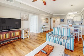 Ein geräumiges Wohnzimmer mit Fernseher, einem gestreiften Sofa und einem Couchtisch.