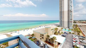 A high-rise hotel overlooking a beach with a parking lot and a pool. - 7th-floor resort studio with partial Gulf views, outdoor pool, gym & hot tub (Panama City Beach)