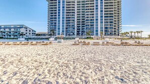 A beachfront hotel with multiple high-rise buildings, a sandy beach, and some palm trees. - Centrally located condo w/ private balcony, Pool & Hot tub (Panama City Beach)