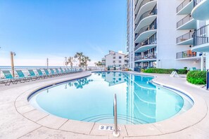 Une piscine équipée de chaises longues, avec une indication de la profondeur (3 pieds), et un bâtiment doté de balcons.