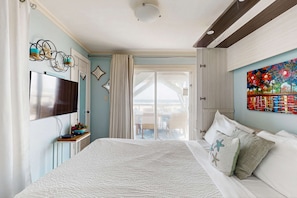 Un dormitorio con cama, televisión, un cuadro y vistas al exterior.
