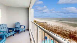 Un balcon avec deux fauteuils Adirondack, une piscine et une vue sur la plage.