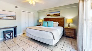 A bedroom with a bed, bedside tables, a desk, and a ceiling fan. - Adorable condo across from the Gulf with central AC, deck, pool & grill (Perdido Key)