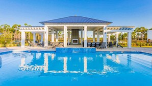 Ein Swimmingpool mit überdachtem Pavillon, Liegestühlen und blauem Himmel.