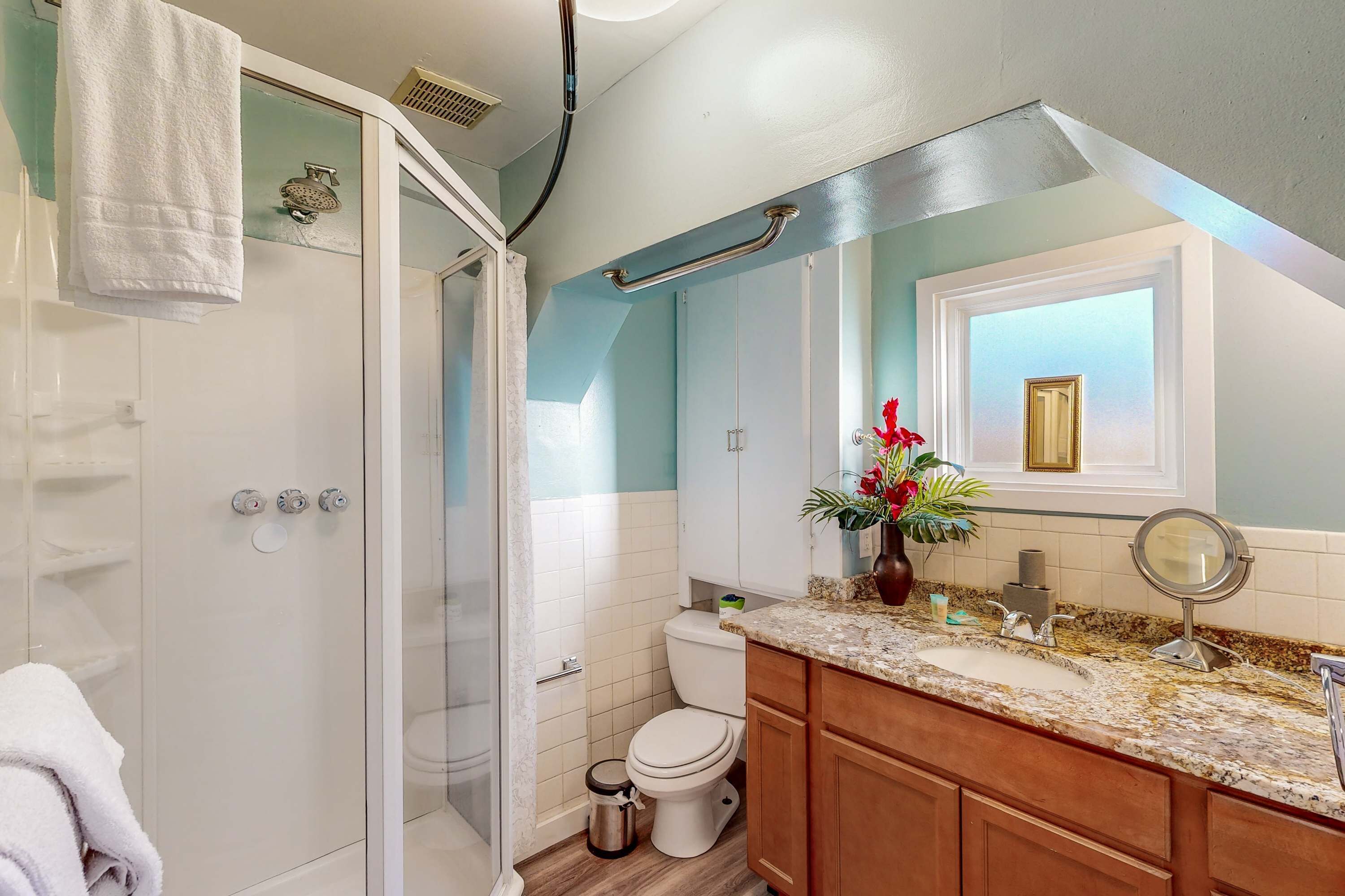 A bathroom with a shower, toilet, sink, and vanity.