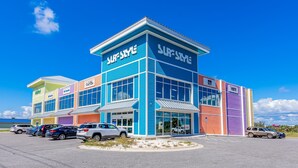 Un immeuble à plusieurs étages arborant une enseigne « SURF STYLE », avec un parking contenant plusieurs voitures.