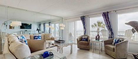 A spacious living area with a large mirror, a sofa, armchairs, and a coffee table.