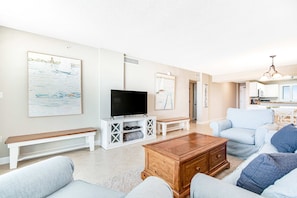 A living room with a TV, bench, sofa, and coffee table. - Gorgeous Oceanfront condo with washer/dryer, Gulf-front balcony & pool/hot tub (Perdido Key)