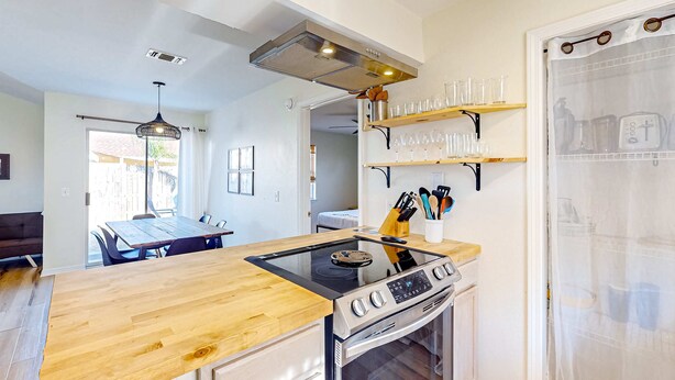 A modern kitchen with a wooden countertop, stainless steel appliances, and a dining area with a table and chairs. - Updated home near the beach with patio, AC, & private WD (Panama City)