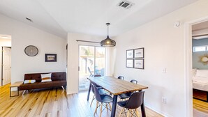 A modern living room with a wooden dining table, black chairs, a brown sofa, and a ceiling light fixture. - Updated home near the beach with patio, AC, & private WD (Panama City)