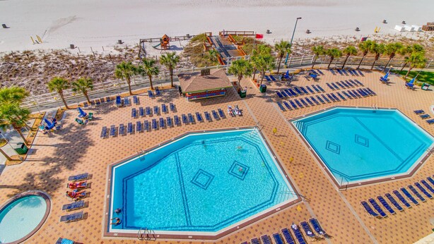 Un resort con diverse piscine, lettini prendisole e una spiaggia.