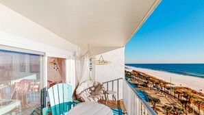 Un balcone con vista sulla spiaggia, una sedia, un tavolino e un addobbo appeso.