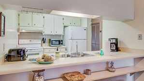 Una cucina con mobili bianchi, un forno a microonde, un tostapane, un lavello e una macchina per il caffè.