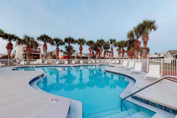 A swimming pool with a 3ft depth limit, surrounded by palm trees and white lounge chairs. - Wonderful vacation retreat close to the beach w/WiFi, central AC, & shared pool (Panama City Beach)