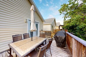A patio with a table and chairs, a barbecue grill, and a wooden deck. - Wonderful vacation retreat close to the beach w/WiFi, central AC, & shared pool (Panama City Beach)