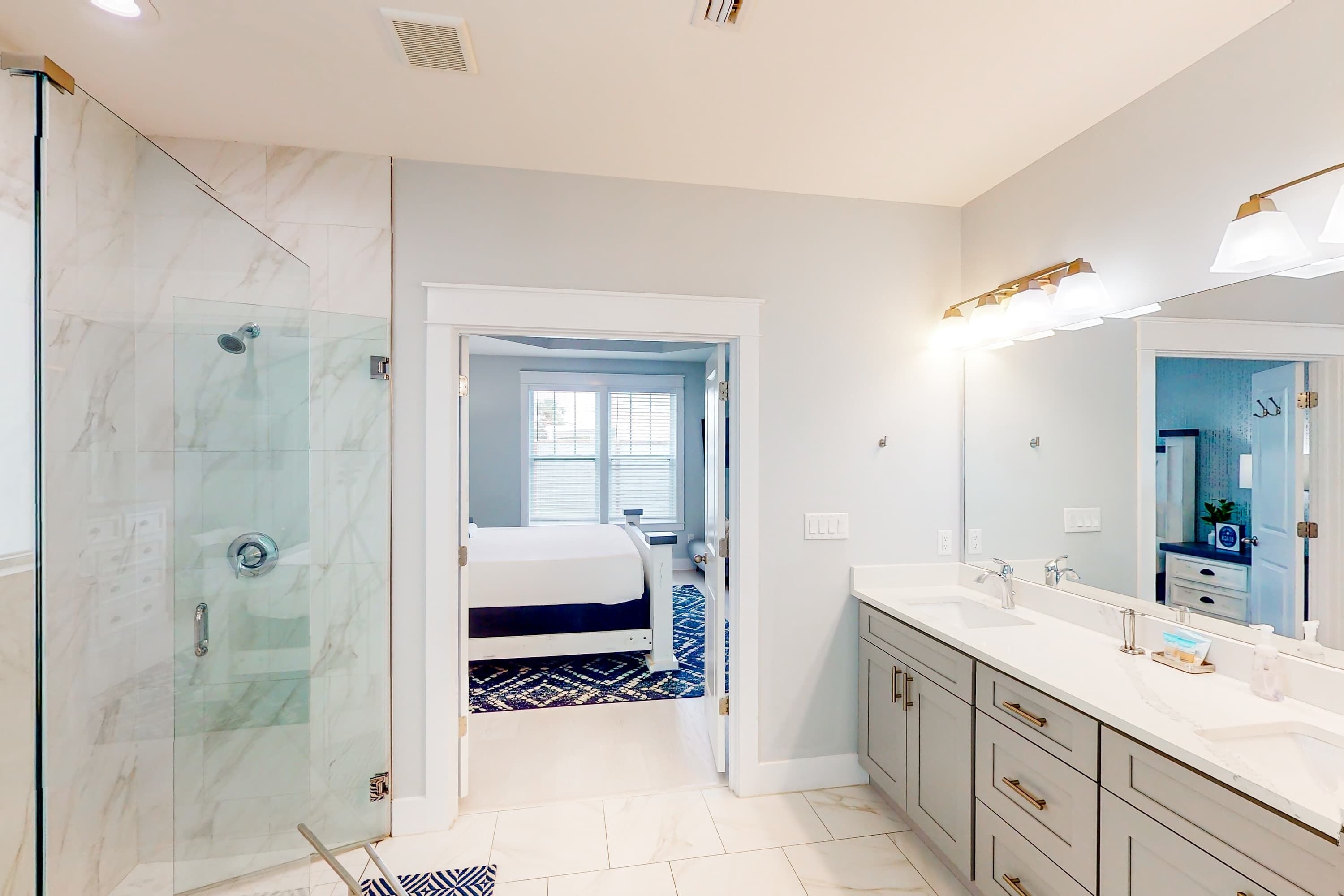 Un baño moderno con cabina de ducha de vidrio, un espejo grande y un vestidor.