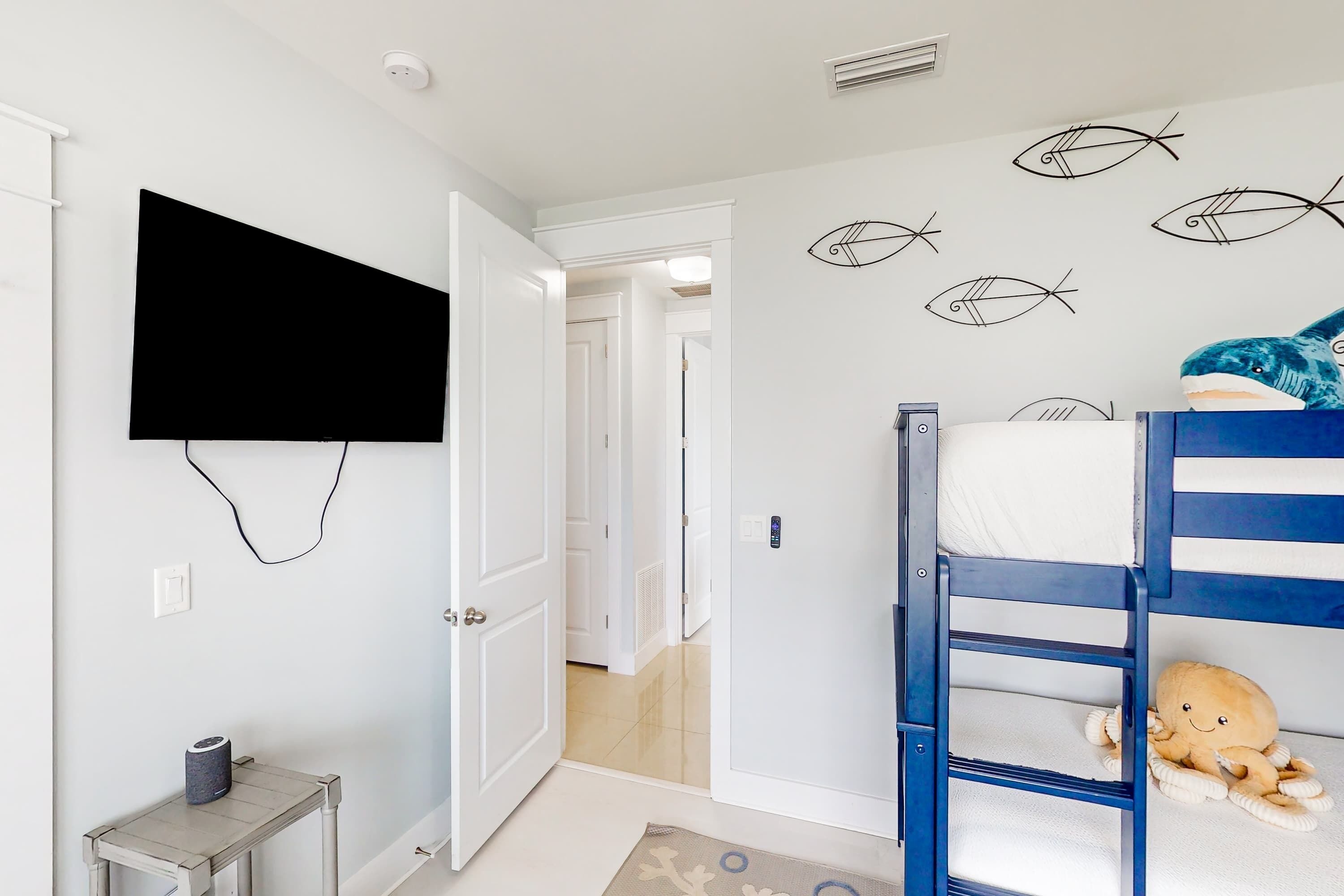 A child's bedroom with bunk beds, a television mounted on the wall, and a fish decal.