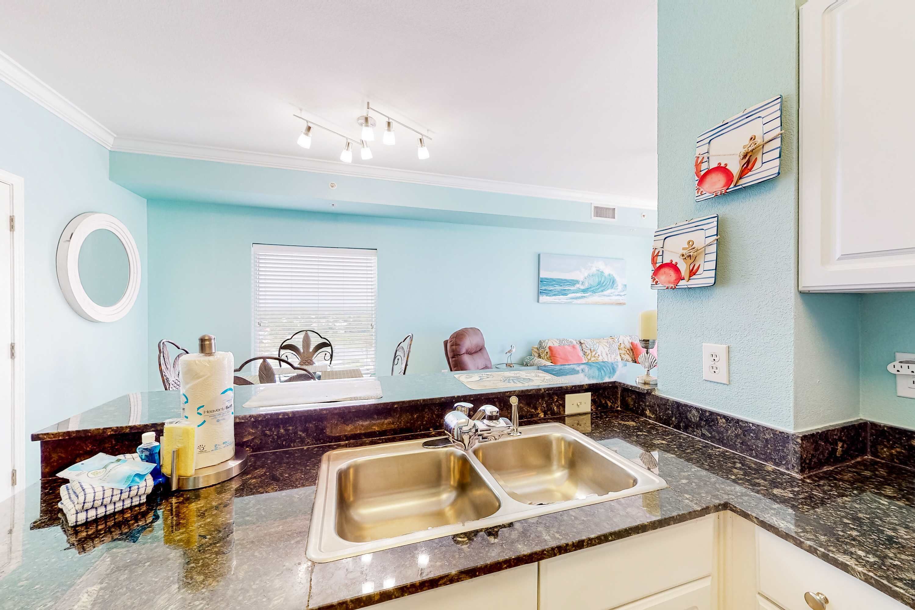 A kitchen with a double sink, a marble countertop, and light blue walls.