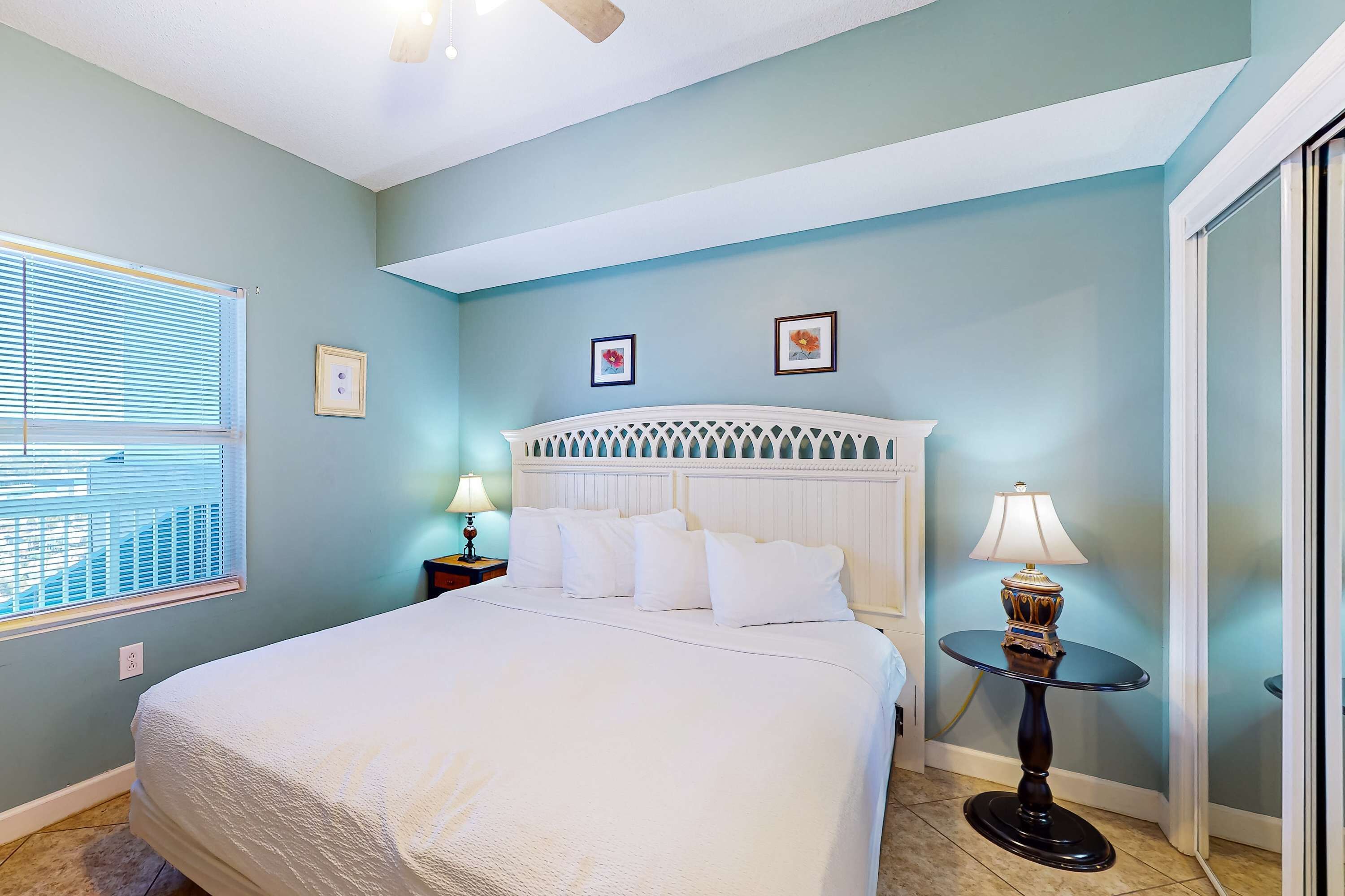 A bedroom with a bed, a nightstand, a lamp, and two framed pictures on the wall.