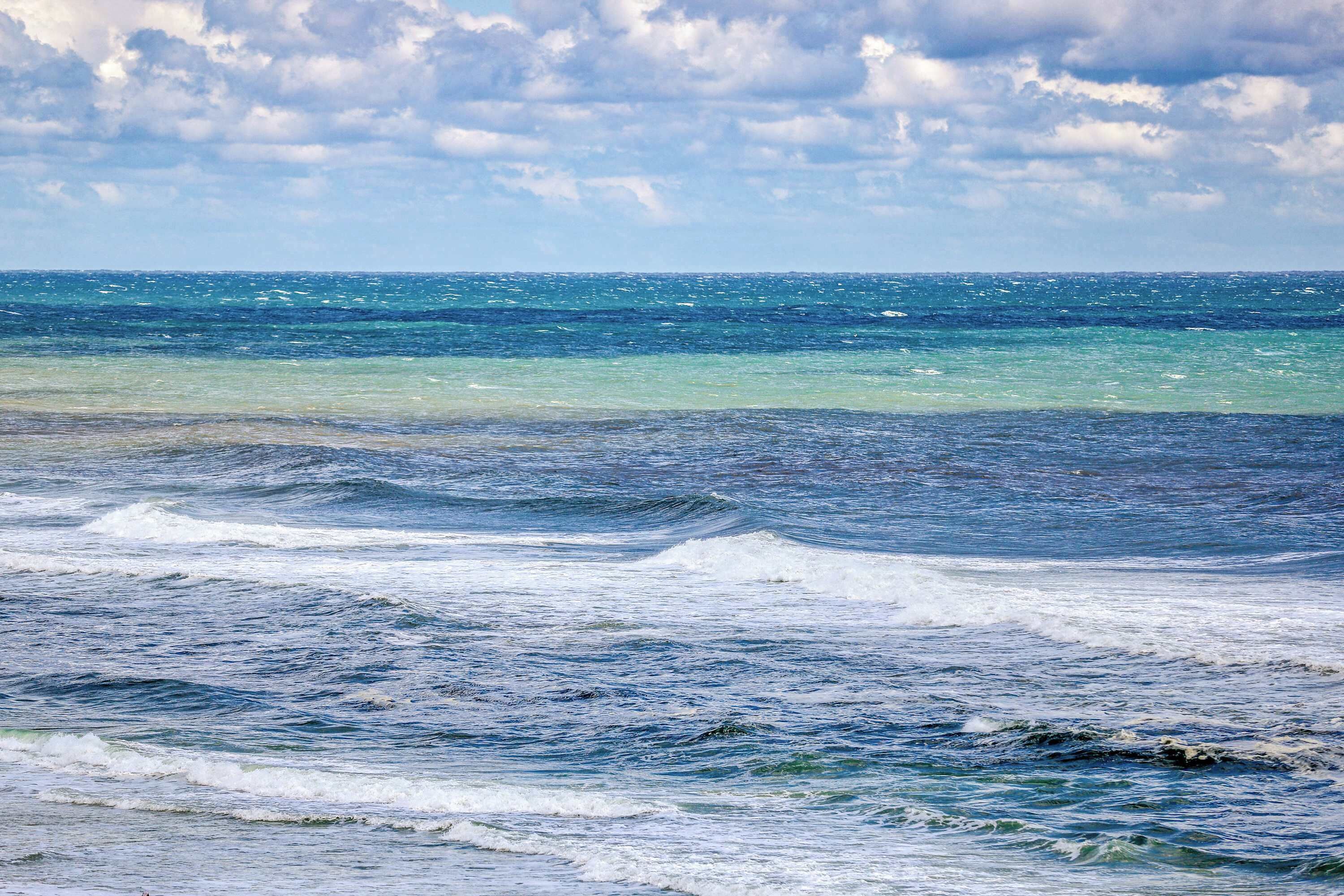 A view of the ocean with waves and a cloudy sky.