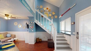 Ein Wohnzimmer mit blauer Wand, einer Treppe und einer Tür mit Fenster.