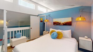 Ein Schlafzimmer mit Bett, einer Bank, einem Nachttisch und einer Wandlampe.