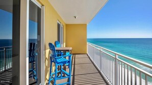 A balcony with a view of the ocean, a table with chairs, and a security camera. - Gulf-front condo with pier views, balcony, heated pool, gym & AC (Panama City Beach)