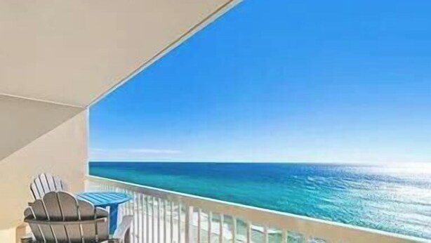Un balcone con vista sull'oceano, una sedia e una ringhiera.