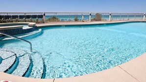 Una piscina con acqua cristallina blu, design curvo e vista sull'oceano sullo sfondo.