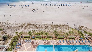 Et strandresort med swimmingpool, liggestole og en sandstrand.