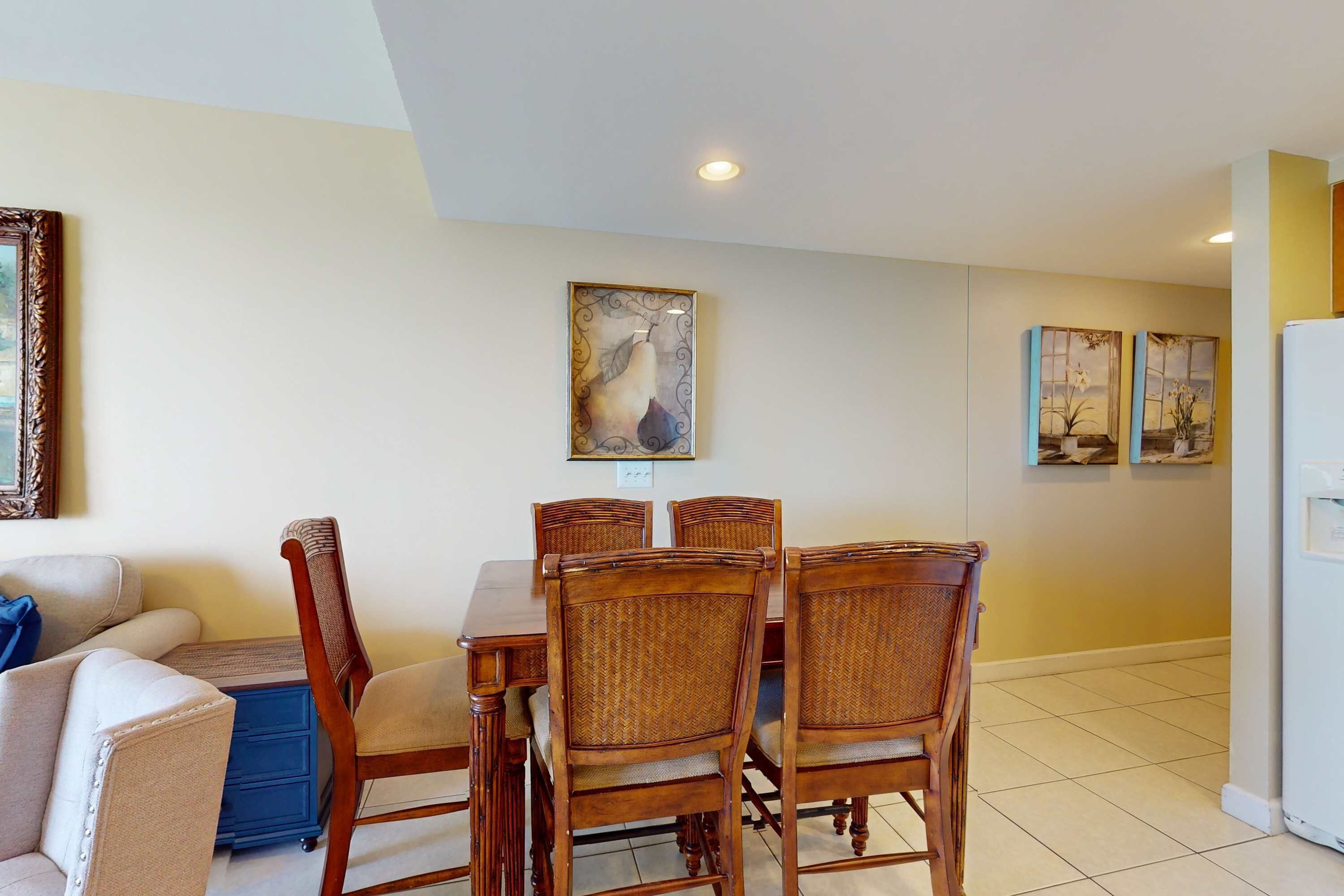 Un comedor con mesa y sillas de madera, un sofá y decoración en la pared.