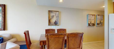Un comedor con mesa y sillas de madera, un sofá y decoración en la pared.