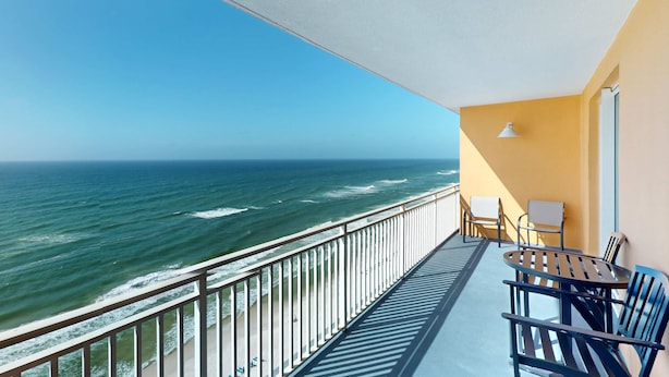 Ein Balkon mit Blick auf das Meer, einem Tisch mit Stühlen und einer Lampe.
