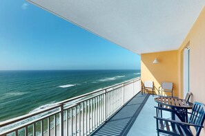 A balcony with a view of the ocean, a table with chairs, and a lamp. - Beachfront Condo, gorgeous views, shared pool and beach access (Panama City Beach)