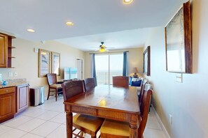 A spacious dining area with a large wooden table, chairs, and a ceiling fan. - Beachfront Condo, gorgeous views, shared pool and beach access (Panama City Beach)