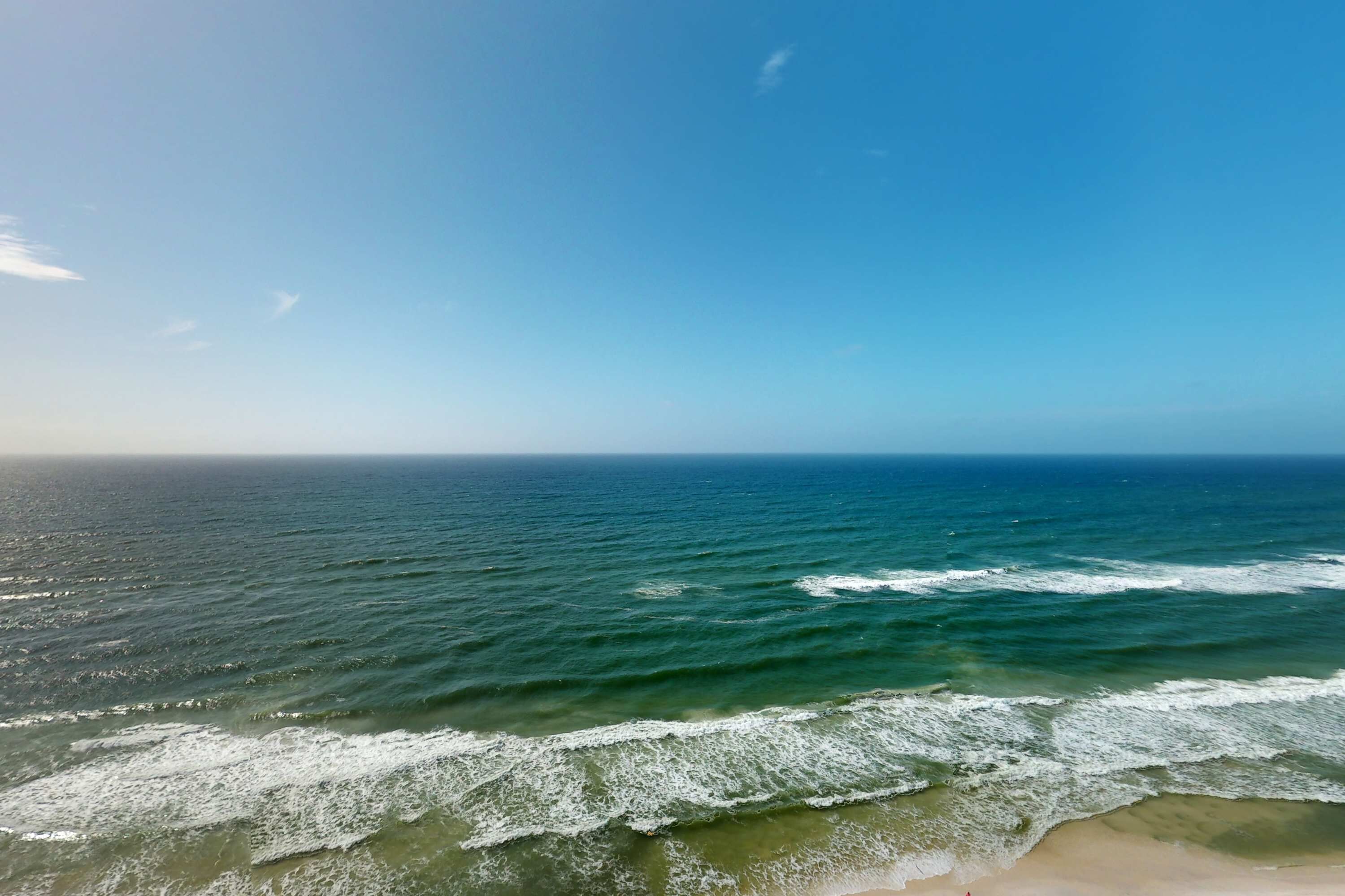 A beach with waves and a clear sky.