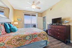 A bedroom with a large bed, a dresser, a television, and a ceiling fan. - Gulf front condo with resort amenities, snack bar, and Lazy River (Panama City Beach)