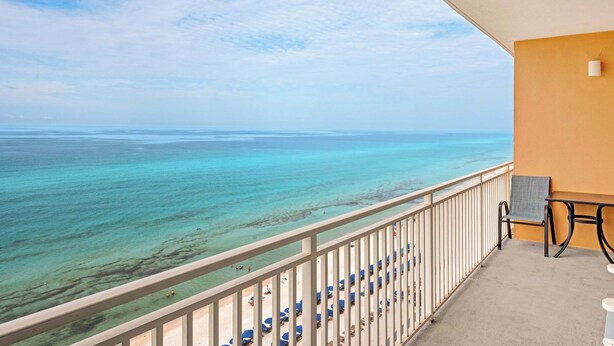 Ein Balkon mit Blick auf das Meer, ein Tisch, ein Stuhl und ein Geländer.