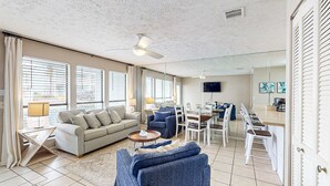 A spacious living room with a sofa, chairs, a dining area, and a ceiling fan. - Condo in Panama City Beach with pool & beach access (Panama City Beach)