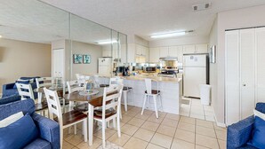 A compact living space with a dining area, kitchenette, and a mirrored wall. - Condo in Panama City Beach with pool & beach access (Panama City Beach)