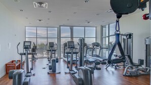A gym with various exercise equipment, large windows, and a wooden floor. - Wonderfully decorated Gulf-view condo | Pool | Hot tub (Panama City Beach)