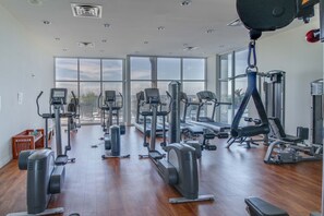 Ein Fitnessstudio mit unterschiedlichen Trainingsgeräten, großen Fenstern und Holzboden.